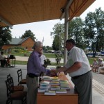 Grāmatas atvēršanas sarīkojums Asūnē 2013.gada 22.jūnijā. Grāmatu saņem bijušais Asūnes skolas direktors Jānis Belkovskis. Foto H.Soms